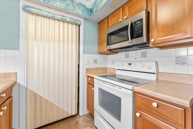 2630 Pearce Dr Unit 108, Clearwater, FL 33764 - kitchen featuring white range with electric cooktop, stainless steel microwave, light countertops, brown cabinets, and tasteful backsplash