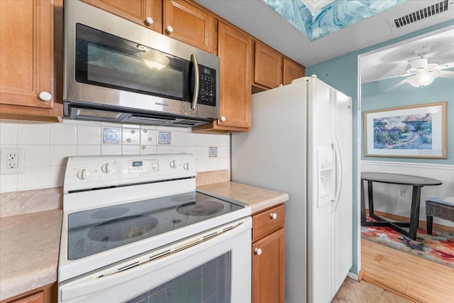 2630 Pearce Dr Unit 108, Clearwater, FL 33764 - kitchen with white appliances, brown cabinets, light countertops, tasteful backsplash, and a ceiling fan