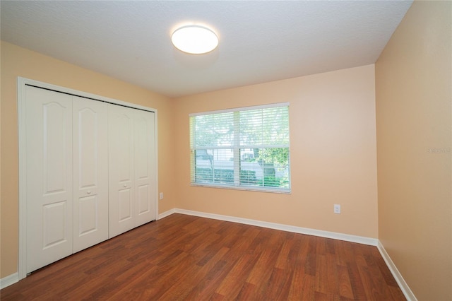 37712 Aaralyn Rd, Zephyrhills, FL 33542 - unfurnished bedroom featuring dark wood finished floors, baseboards, and a closet