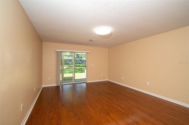 37712 Aaralyn Rd, Zephyrhills, FL 33542 - spare room featuring dark wood-style floors, baseboards, and a textured ceiling