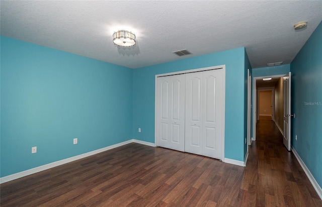 37712 Aaralyn Rd, Zephyrhills, FL 33542 - unfurnished bedroom featuring dark wood-style floors, a closet, baseboards, and a textured ceiling
