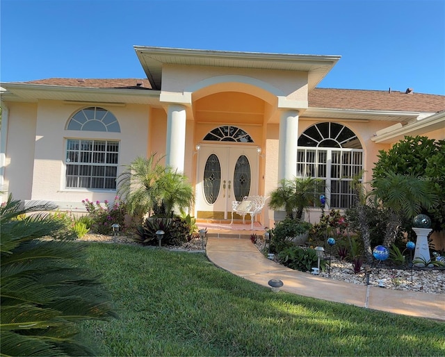 13339 Amberwood St, Hudson, FL 34669 - doorway to property with stucco siding, a yard, and a shingled roof