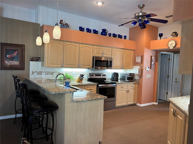 13339 Amberwood St, Hudson, FL 34669 - kitchen with appliances with stainless steel finishes, a peninsula, ceiling fan, light stone countertops, and a kitchen bar