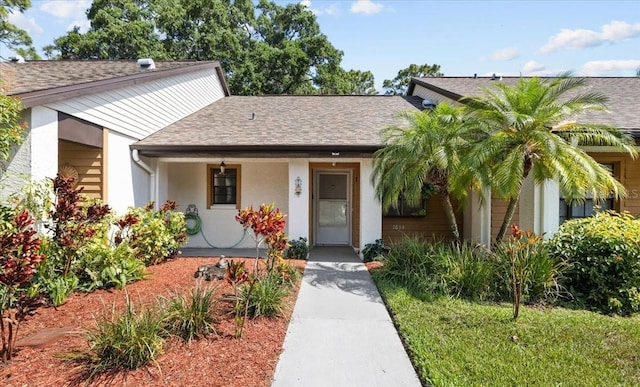 7633 Piping Rock Ct Unit 7633, New Port Richey, FL 34654 - view of front of property with a shingled roof, covered porch, and stucco siding