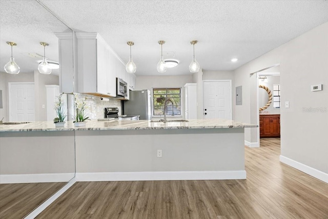 7633 Piping Rock Ct Unit 7633, New Port Richey, FL 34654 - kitchen featuring a sink, appliances with stainless steel finishes, light stone counters, light wood-style flooring, and a textured ceiling