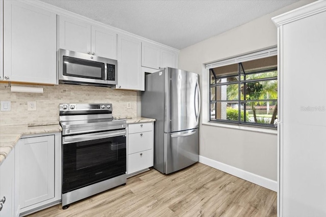 7633 Piping Rock Ct Unit 7633, New Port Richey, FL 34654 - kitchen with stainless steel appliances, light wood-style flooring, tasteful backsplash, white cabinetry, and a textured ceiling