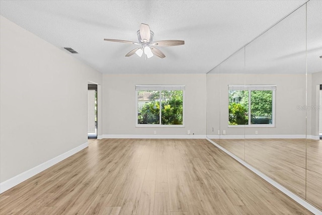 7633 Piping Rock Ct Unit 7633, New Port Richey, FL 34654 - unfurnished living room featuring healthy amount of natural light, ceiling fan, light wood-style flooring, baseboards, and a textured ceiling