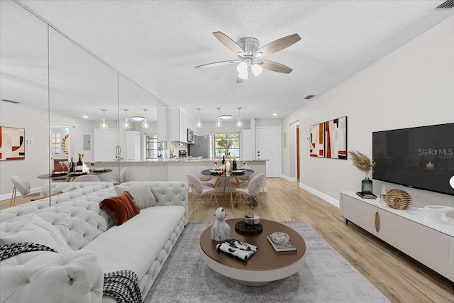 7633 Piping Rock Ct Unit 7633, New Port Richey, FL 34654 - living room with light wood-style floors, a ceiling fan, baseboards, and a textured ceiling