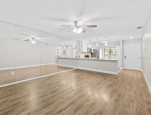 7633 Piping Rock Ct Unit 7633, New Port Richey, FL 34654 - unfurnished living room with ceiling fan, a textured ceiling, light wood-style flooring, baseboards, and a sink