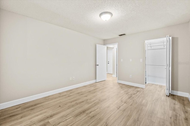 7633 Piping Rock Ct Unit 7633, New Port Richey, FL 34654 - unfurnished bedroom featuring light wood-style floors, a textured ceiling, baseboards, a spacious closet, and a closet