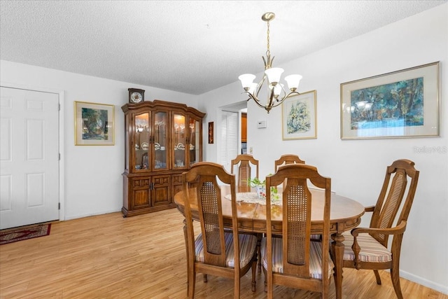 8174 Terrace Garden Dr N Unit 204, Saint Petersburg, FL 33709 - dining area with a chandelier, light wood-style floors, and a textured ceiling
