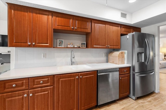 8174 Terrace Garden Dr N Unit 204, Saint Petersburg, FL 33709 - kitchen with appliances with stainless steel finishes, a sink, light countertops, light wood-style flooring, and decorative backsplash