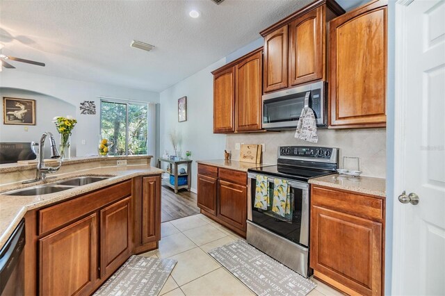6736 Breezy Palm Dr, Riverview, FL 33578 - kitchen featuring stainless steel appliances, a sink, a textured ceiling, ceiling fan, and brown cabinets