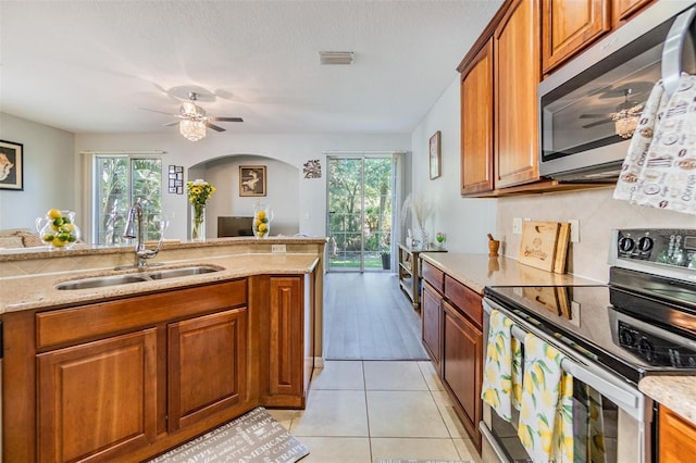 6736 Breezy Palm Dr, Riverview, FL 33578 - kitchen featuring stainless steel appliances, a sink, brown cabinets, and arched walkways