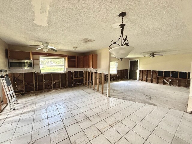 14318 Guava St, Hudson, FL 34667 - unfurnished living room with ceiling fan, a wainscoted wall, a textured ceiling, and light tile patterned floors