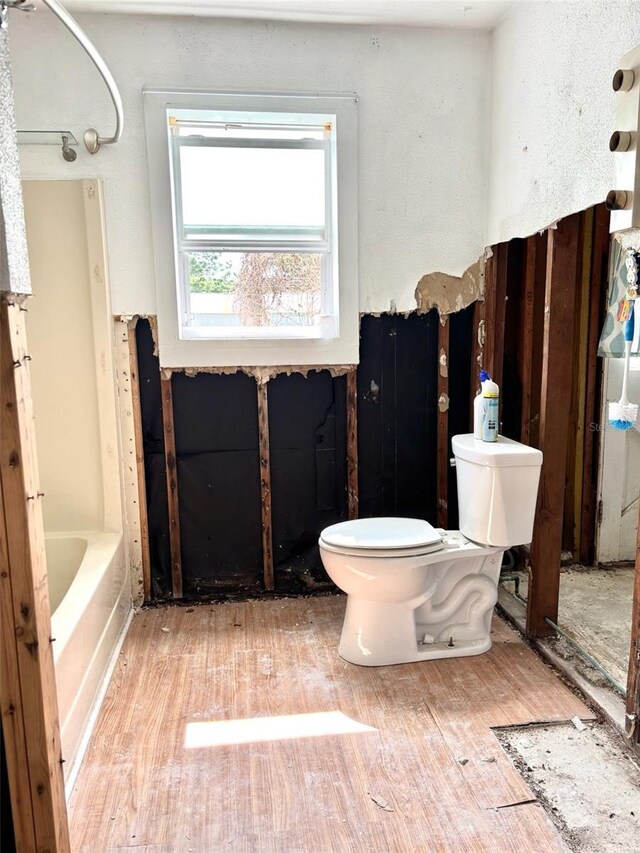 14318 Guava St, Hudson, FL 34667 - full bathroom featuring toilet, wood finished floors, a tub to relax in, and a shower
