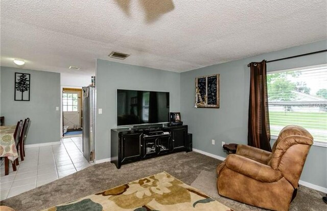14318 Guava St, Hudson, FL 34667 - living room featuring a textured ceiling, baseboards, tile patterned flooring, and carpet flooring