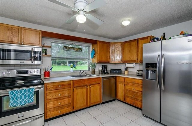 14318 Guava St, Hudson, FL 34667 - kitchen with stainless steel appliances, a sink, brown cabinets, light countertops, and a textured ceiling