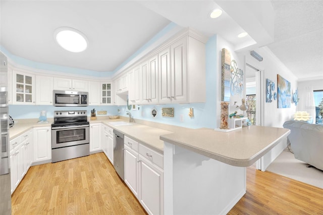 2700 Bayshore Blvd Unit 11308, Dunedin, FL 34698 - kitchen featuring stainless steel appliances, a sink, a peninsula, glass insert cabinets, and light wood-style floors