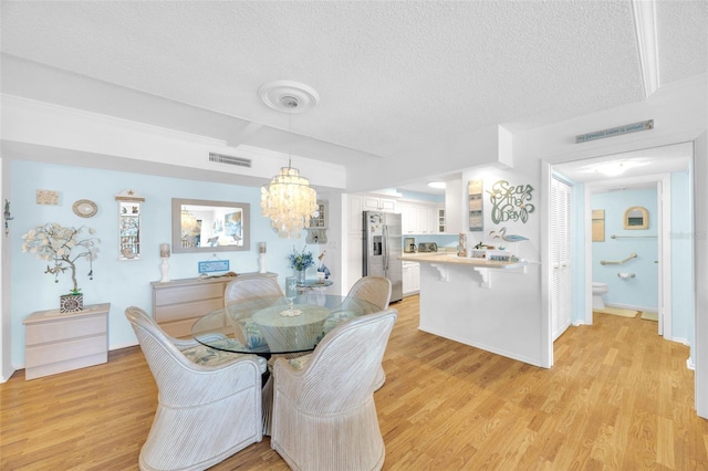 2700 Bayshore Blvd Unit 11308, Dunedin, FL 34698 - dining room featuring a textured ceiling, light wood-style flooring, and a chandelier