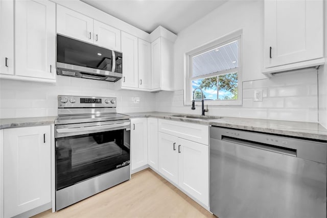 8433 101st Ave, Seminole, FL 33777 - kitchen featuring appliances with stainless steel finishes, a sink, light stone counters, tasteful backsplash, and white cabinetry
