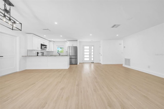 8433 101st Ave, Seminole, FL 33777 - unfurnished living room featuring light wood-style flooring, baseboards, recessed lighting, and a sink
