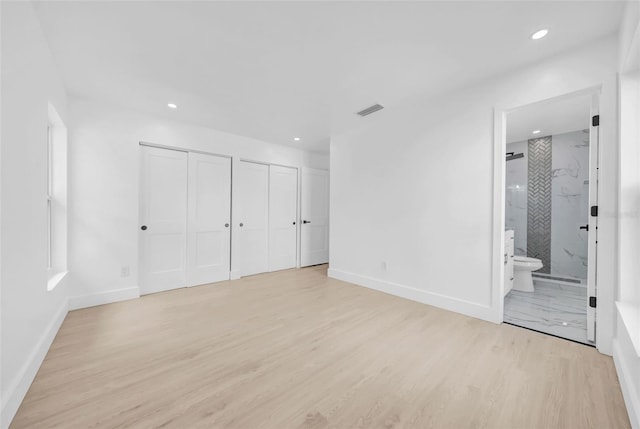 8433 101st Ave, Seminole, FL 33777 - unfurnished bedroom featuring two closets, light wood-style floors, baseboards, recessed lighting, and connected bathroom