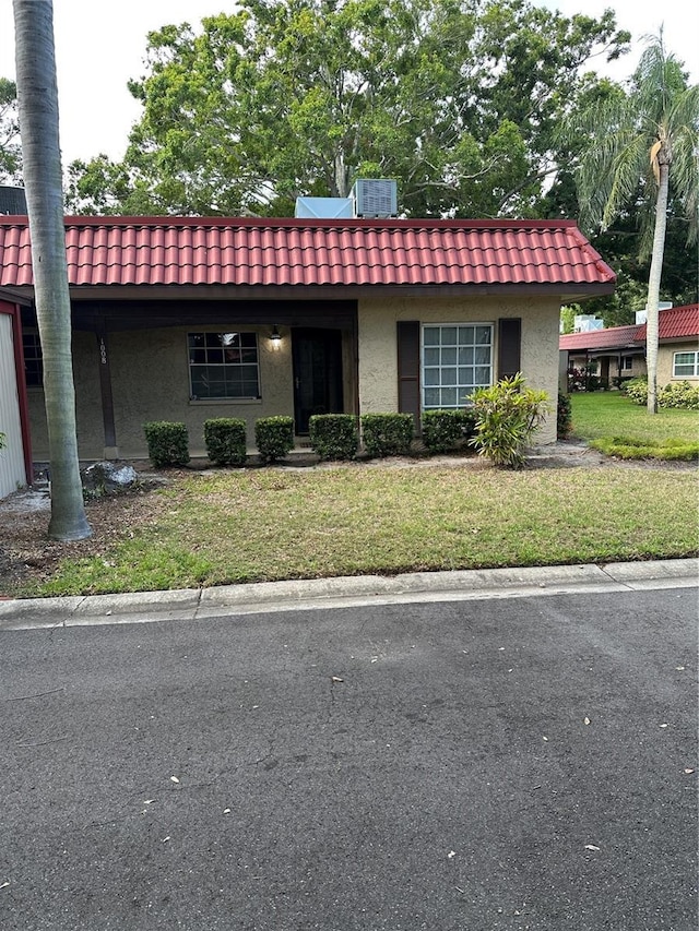 601 N Hercules Ave Unit 1008, Clearwater, FL 33765 - view of front of home featuring stucco siding, a tiled roof, a front lawn, and mansard roof