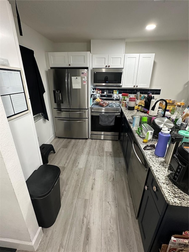601 N Hercules Ave Unit 1008, Clearwater, FL 33765 - kitchen with appliances with stainless steel finishes, light wood-style flooring, white cabinetry, and light stone countertops