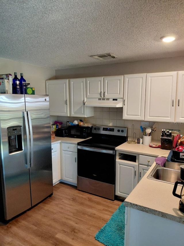 7317 Mitchell Ranch Rd, New Port Richey, FL 34655 - kitchen with stainless steel appliances, under cabinet range hood, a textured ceiling, and white cabinets