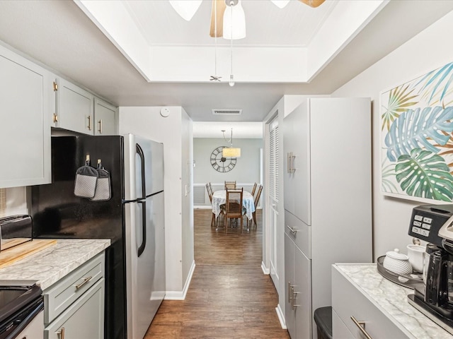 10216 Regal Dr Unit 409, Largo, FL 33774 - kitchen with wood finished floors, a tray ceiling, baseboards, light stone counters, and ceiling fan