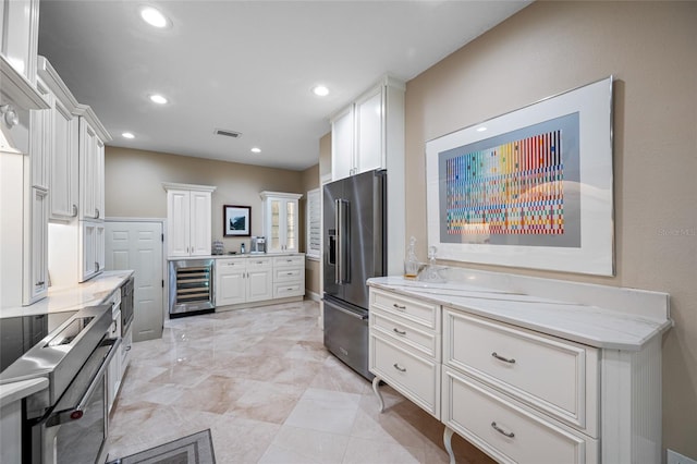 903 Pinellas Bayway S Unit 103, Tierra Verde, FL 33715 - kitchen with stainless steel appliances, beverage cooler, white cabinets, recessed lighting, and light stone counters