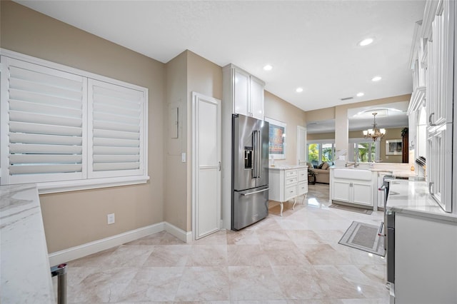 903 Pinellas Bayway S Unit 103, Tierra Verde, FL 33715 - kitchen featuring high quality fridge, a chandelier, baseboards, light stone counters, and white cabinets
