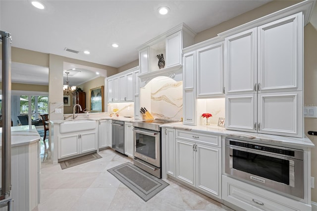 903 Pinellas Bayway S Unit 103, Tierra Verde, FL 33715 - kitchen with appliances with stainless steel finishes, a sink, a chandelier, white cabinets, and recessed lighting