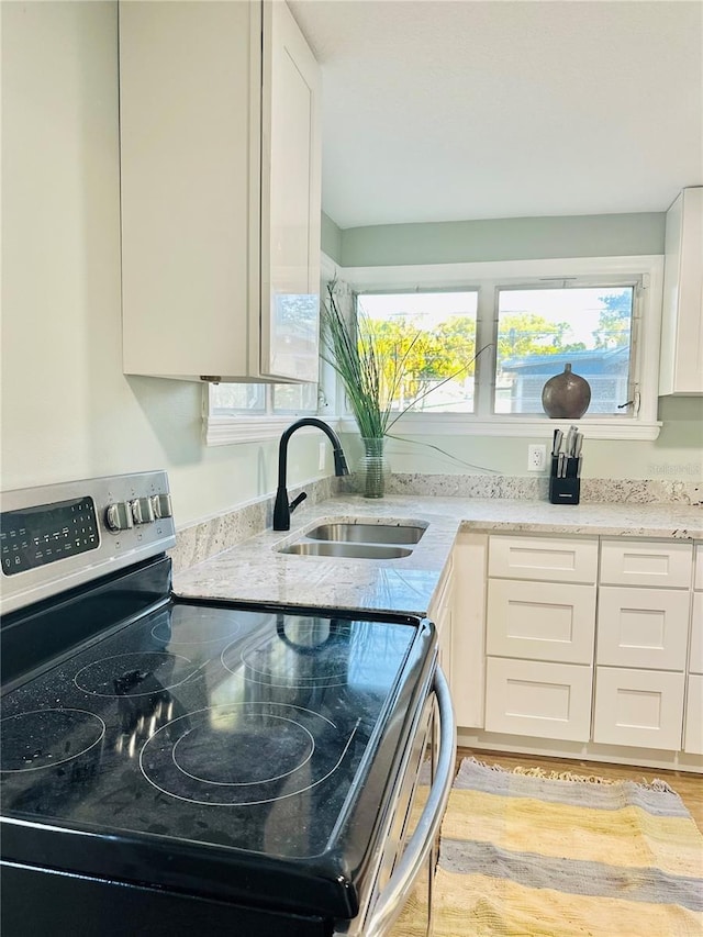 5654 12th St, Zephyrhills, FL 33542 - kitchen featuring stainless steel range with electric cooktop, a sink, white cabinets, and plenty of natural light