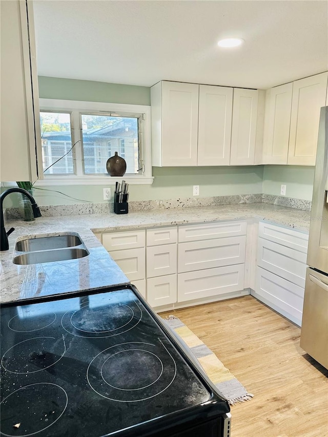 5654 12th St, Zephyrhills, FL 33542 - kitchen featuring black / electric stove, a sink, white cabinetry, stainless steel fridge with ice dispenser, and light wood finished floors