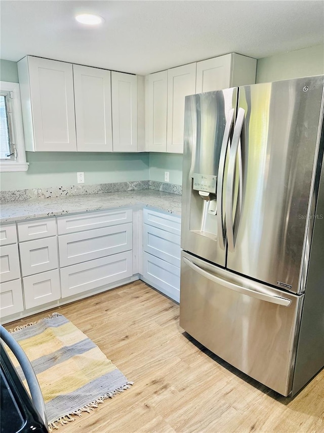 5654 12th St, Zephyrhills, FL 33542 - kitchen with stainless steel refrigerator with ice dispenser, white cabinetry, light wood-style floors, and light stone countertops