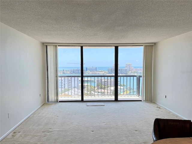 400 Island Way Unit 1402, Clearwater Beach, FL 33767 - unfurnished living room featuring floor to ceiling windows, carpet, a textured ceiling, a view of city, and baseboards
