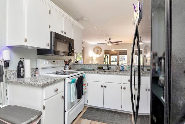 11201 122nd Ave Unit 167, Largo, FL 33778 - kitchen featuring black appliances, white cabinetry, a ceiling fan, and light wood-style flooring