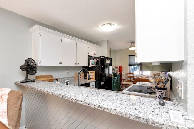 11201 122nd Ave Unit 167, Largo, FL 33778 - kitchen featuring black fridge with ice dispenser, light countertops, white cabinets, stove, and a peninsula