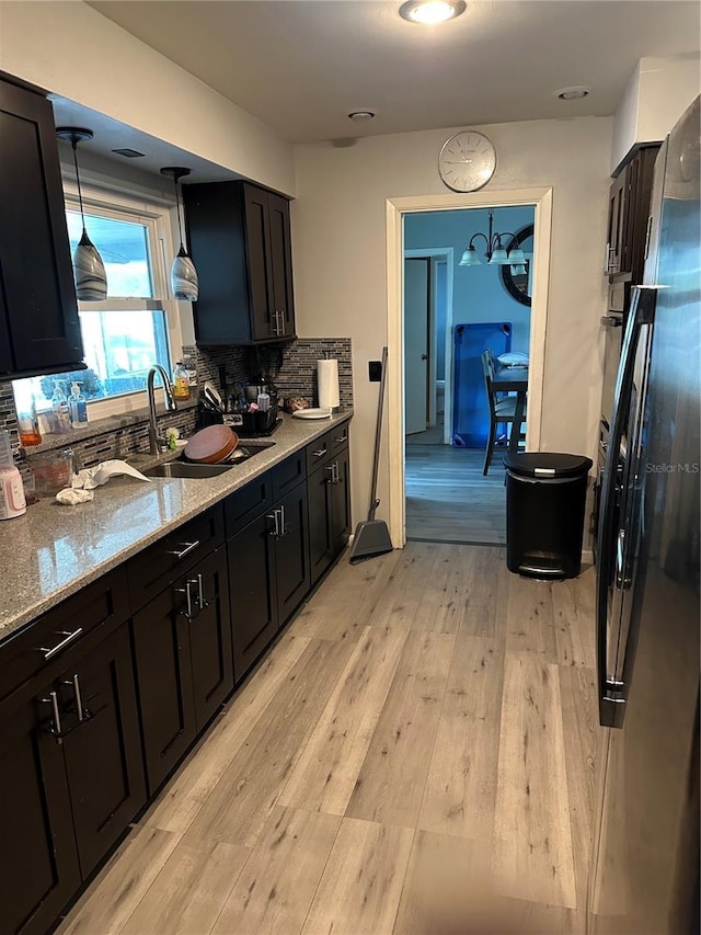 2198 Academy Dr, Clearwater, FL 33764 - kitchen featuring light wood-type flooring, backsplash, light stone counters, a sink, and freestanding refrigerator