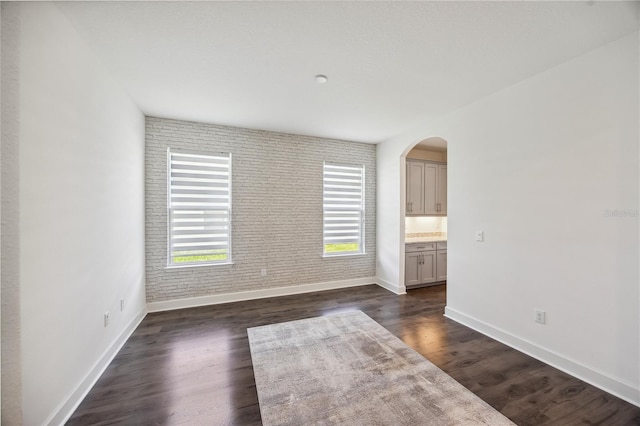 17668 Bright Wheat Dr, Lithia, FL 33547 - empty room featuring baseboards, arched walkways, and dark wood-style floors