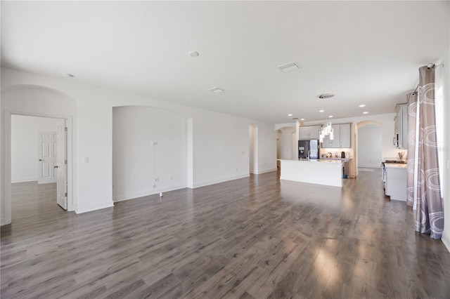17668 Bright Wheat Dr, Lithia, FL 33547 - unfurnished living room featuring arched walkways, dark wood finished floors, recessed lighting, and baseboards
