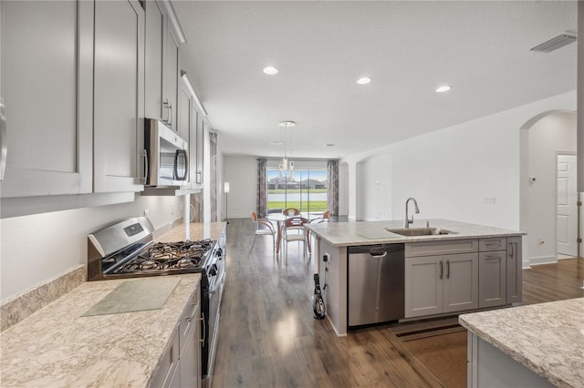 17668 Bright Wheat Dr, Lithia, FL 33547 - kitchen featuring stainless steel appliances, a sink, arched walkways, dark wood-type flooring, and a kitchen island with sink