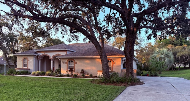 13133 Roseanna Dr, Spring Hill, FL 34609 - view of front facade with stucco siding, a front yard, concrete driveway, and roof with shingles