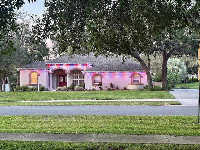13133 Roseanna Dr, Spring Hill, FL 34609 - view of front of property featuring a front lawn, stucco siding, and a shingled roof