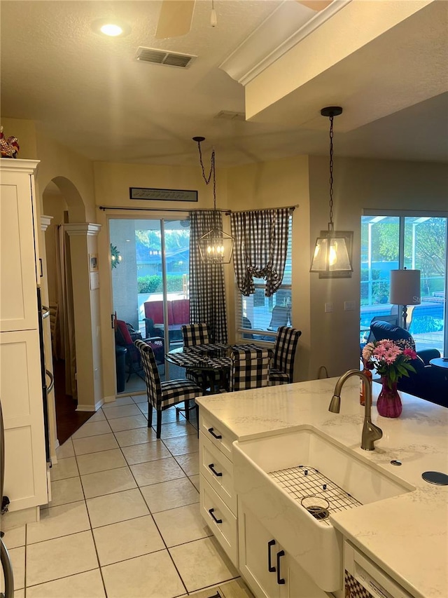 13133 Roseanna Dr, Spring Hill, FL 34609 - kitchen with arched walkways, white cabinets, light tile patterned flooring, and decorative light fixtures