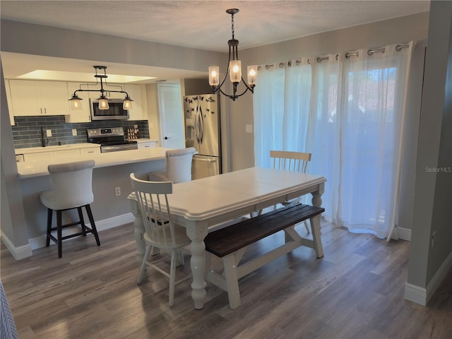 30 Tads Trl, Oldsmar, FL 34677 - dining space featuring dark wood-style floors, a chandelier, baseboards, and a textured ceiling