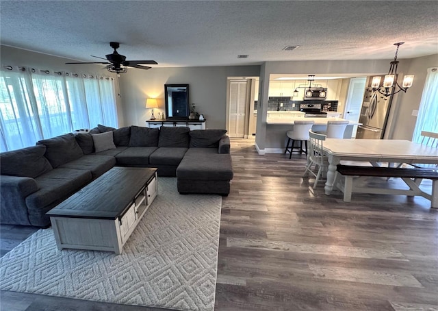 30 Tads Trl, Oldsmar, FL 34677 - living room with a textured ceiling, a chandelier, dark wood finished floors, and a ceiling fan