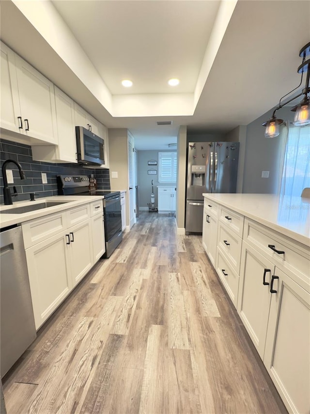 30 Tads Trl, Oldsmar, FL 34677 - kitchen featuring stainless steel appliances, a sink, light wood finished floors, light countertops, and white cabinets